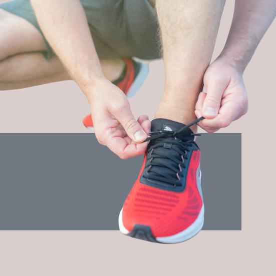 Person i sportstøj gør en løbesko klar ved at binde snørebånd.